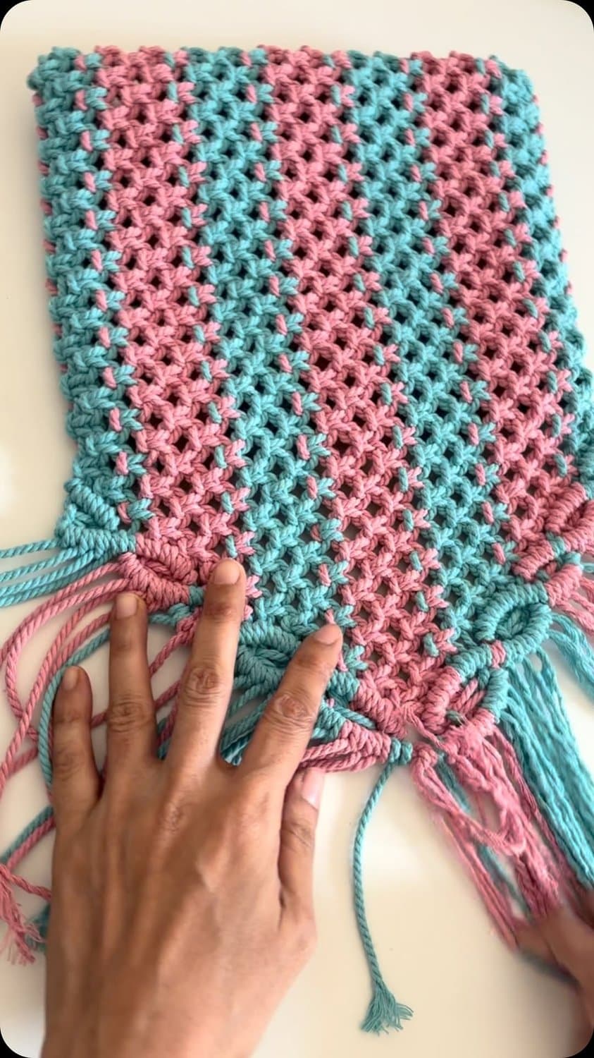 Hands working colourful cotton cord into macrame