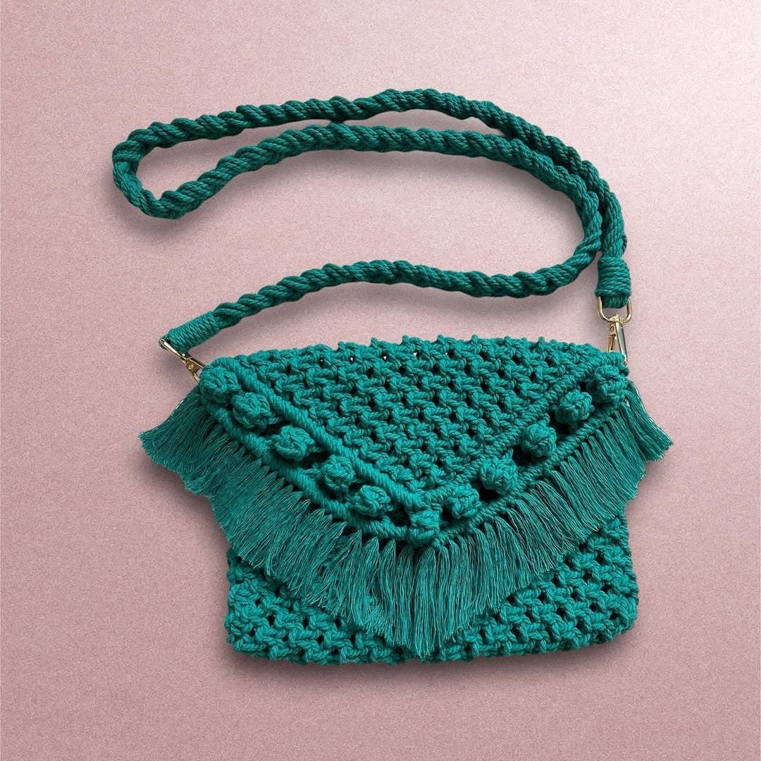 Green macrame shoulder bag against a pink background